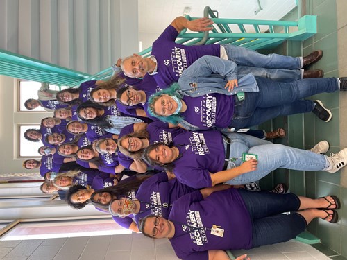 Group of volunteers in purple shirts gather in a stairwell
