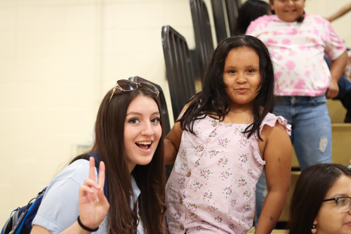 Photo of UCC Volunteer Corps student smiling with a young female student during summer school session in the School gym