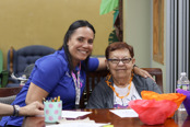 Adult Day Center employee sitting with a female adult day center client doing a craft