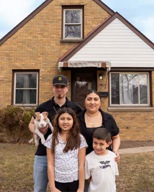 Family standing in front of a house with a dog
