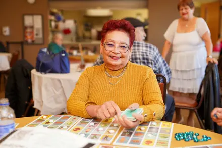 Senior Center client sitting at a table in the UCC Senior Center smiling and playing loteria