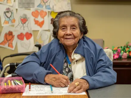 Woman sitting at a craft table drawing a picture