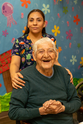 Elderly man laughing with an adult day center employee